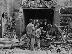 Заключенные собирают трупы жертв бомбардировки.