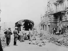 Заключенные грузят трупы в машину.